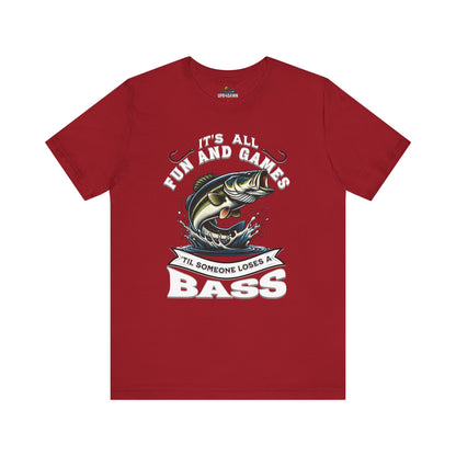 Red unisex fishing tee with a graphic showing a cartoon fish leaping out of water and the words "It's All Fun and Games Until Someone Loses a Bass" in bold text.
