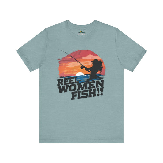A Reel Women Fish - Sunrise / Sunset - T-Shirt featuring a graphic of a lady angler fishing at sunset with the text "reel women fish!" below the image. The design is colorful with a warm-toned backdrop.