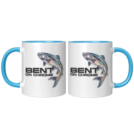 Two white Bent on Chrome - Chrome Salmon accent mugs with blue handles, each featuring a colorful illustration of a fish and the text "bent on chrome" on their surfaces. The mugs are positioned facing each other and feature